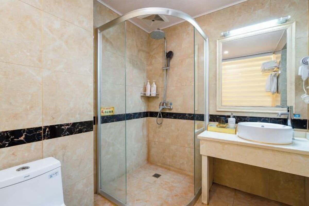 A modern bathroom with a glass-enclosed shower, a white sink, and a mirror above it.