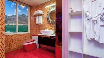 A bathroom with a red floor, a white sink, a mirror, and a window with a view of a body of water.
