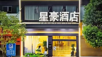 Un hôtel doté d’une enseigne bien visible, d’un panneau indiquant l’emplacement du parking et d’un espace d’entrée bien entretenu.
