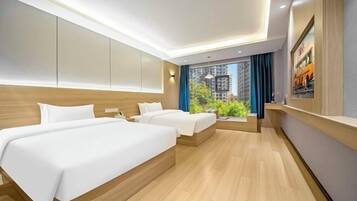 A modern hotel room with two beds, a large window with a view of buildings, and a mounted artwork on the wall.