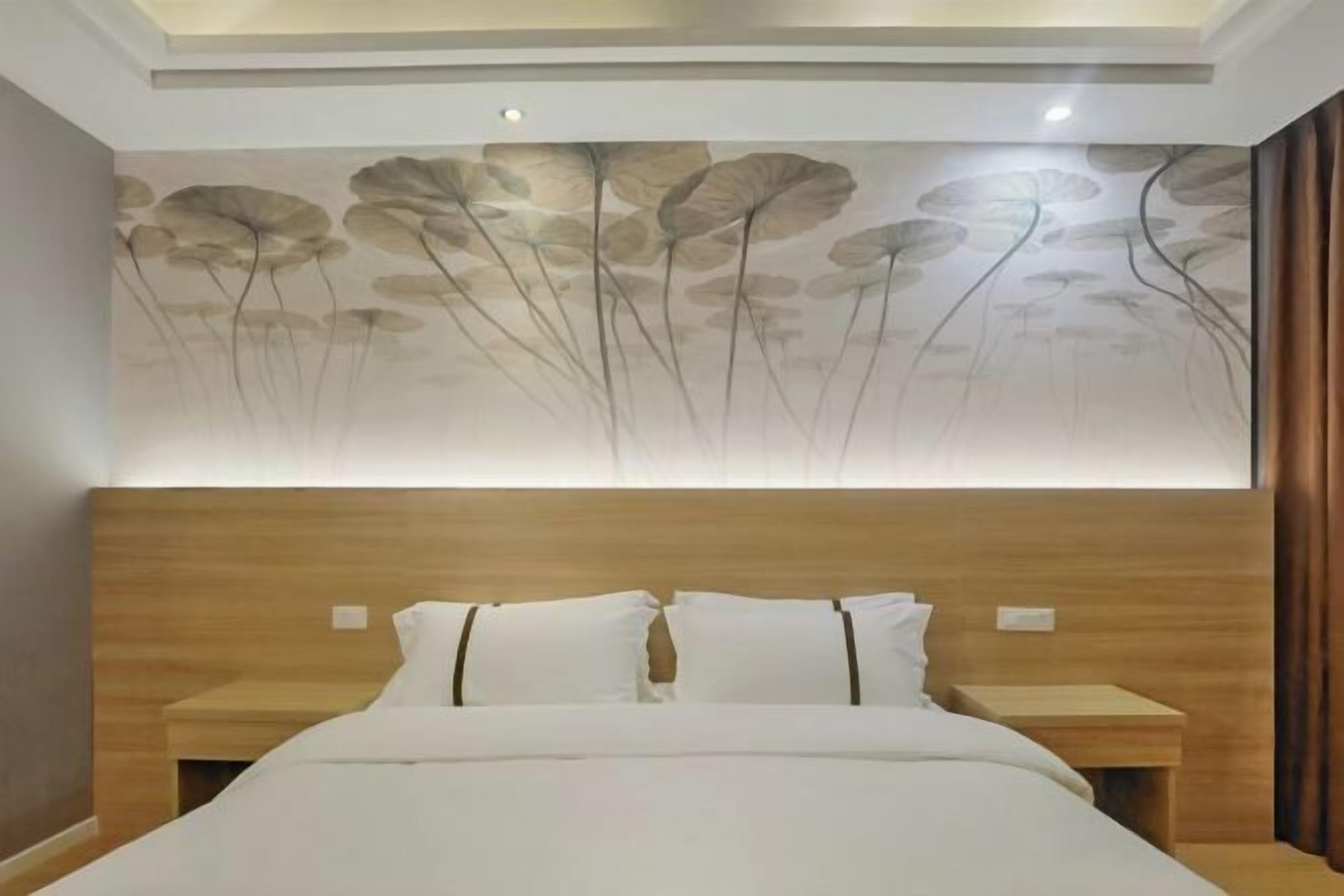 A hotel room with a large bed, wooden headboard, and a wall mural of flowers.