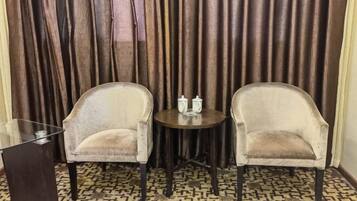 A room with two armchairs, a small round table with two bottles, and a glass table.
