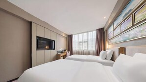 Habitación de hotel con dos camas, televisión, escritorio y ventana con cortinas.
