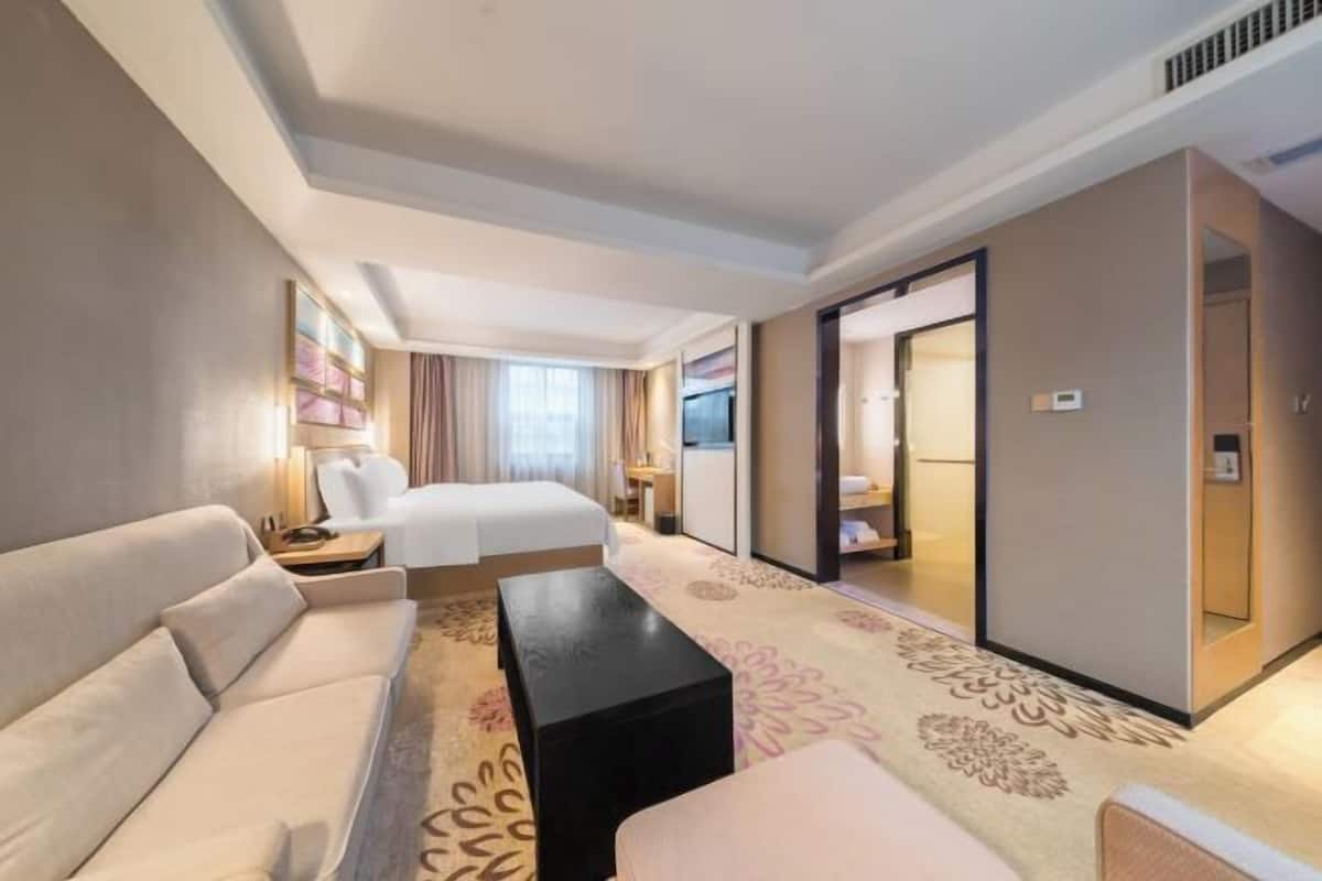 A hotel room with a bed, a sofa, a coffee table, and a desk.