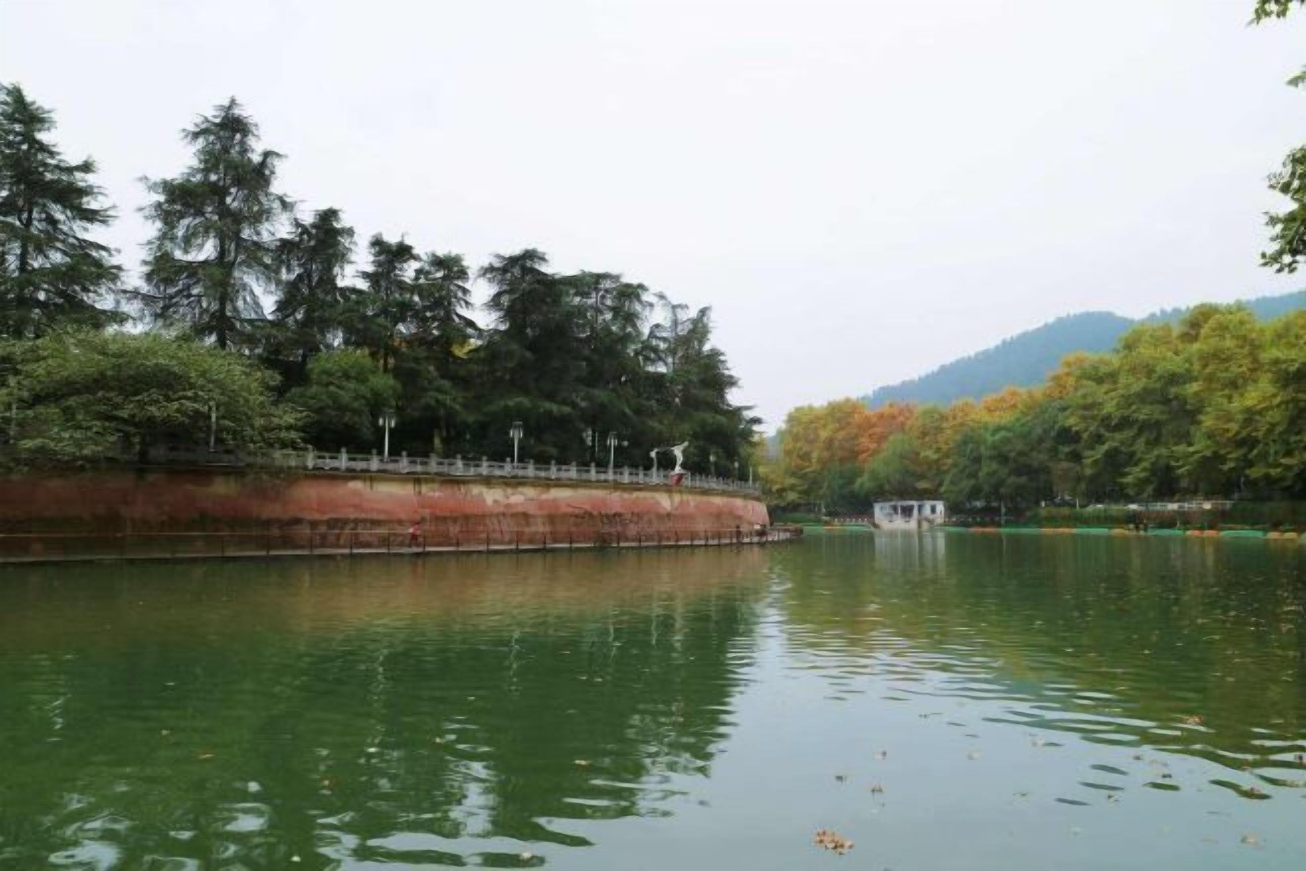 A calm river with a bridge and trees in the background.