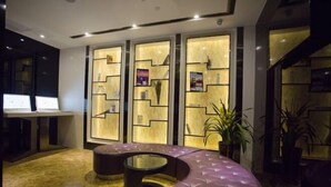 Un vestíbulo moderno con una zona de estar curva, un mostrador de recepción y una pared con paneles iluminados.