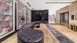 Un vestíbulo moderno con una zona de estar curvilínea, suelo de mármol y una mesa de recepción.