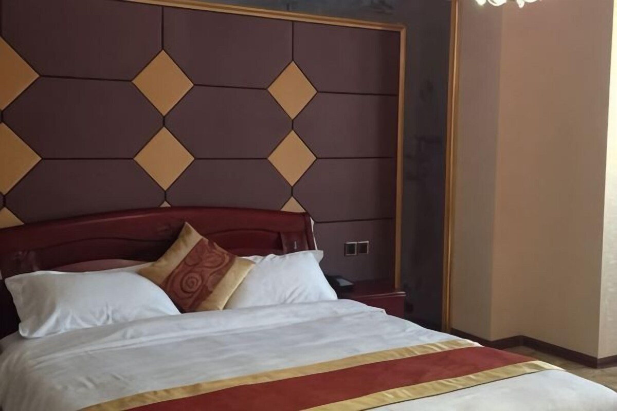 A hotel room with a bed, a headboard with a geometric pattern, and a nightstand.