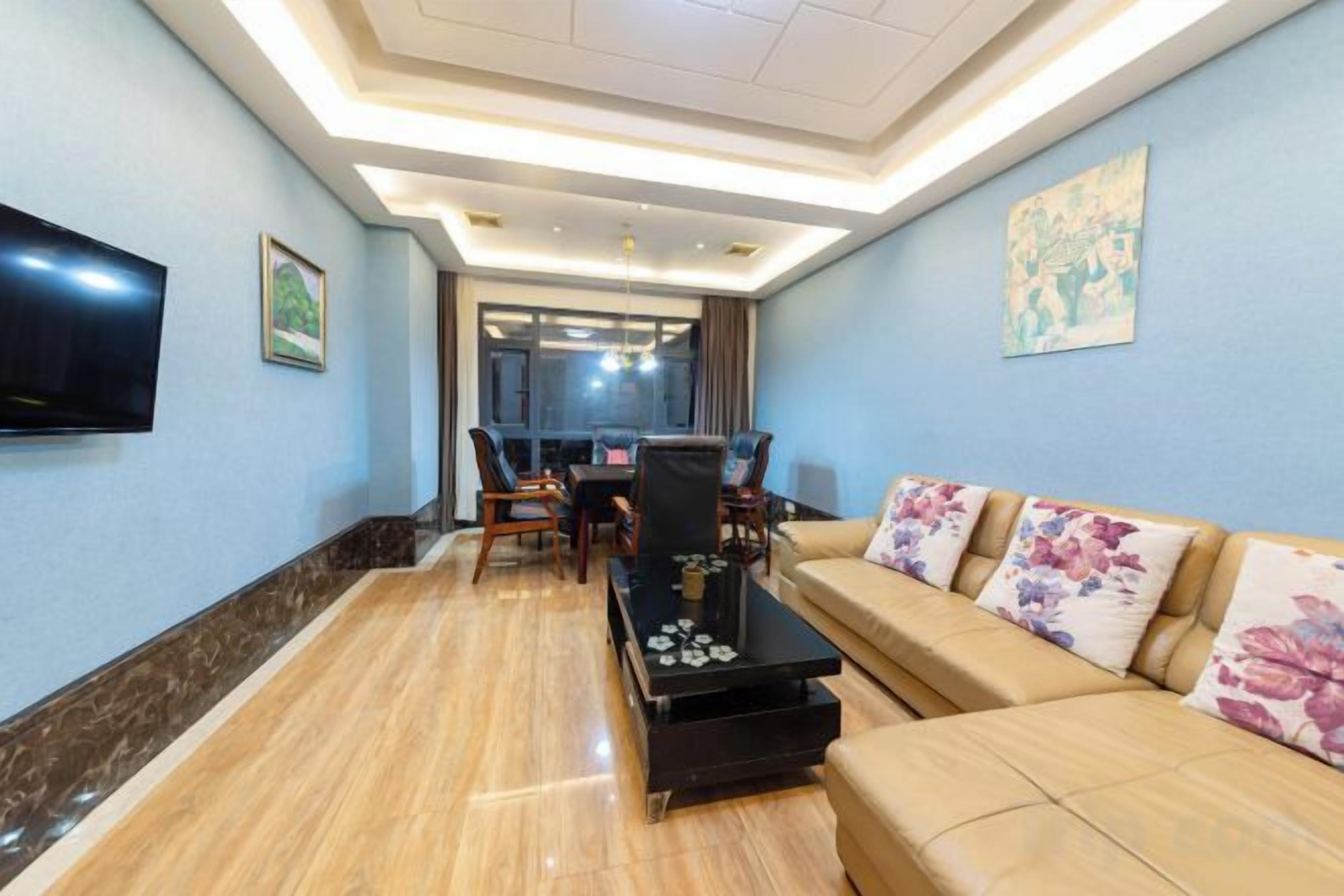A modern living room with a sofa, coffee table, and a flat-screen TV mounted on the wall.
