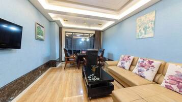 A modern living room with a sofa, coffee table, and a flat-screen TV mounted on the wall.