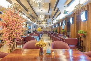 Un restaurante con varias mesas y sillas, techo de madera e iluminación decorativa.
