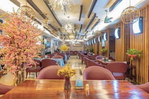 Un restaurante con varias mesas y sillas, techo de madera e iluminación decorativa.