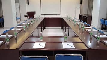 A conference room with a long table, chairs, water bottles, and a projector screen.