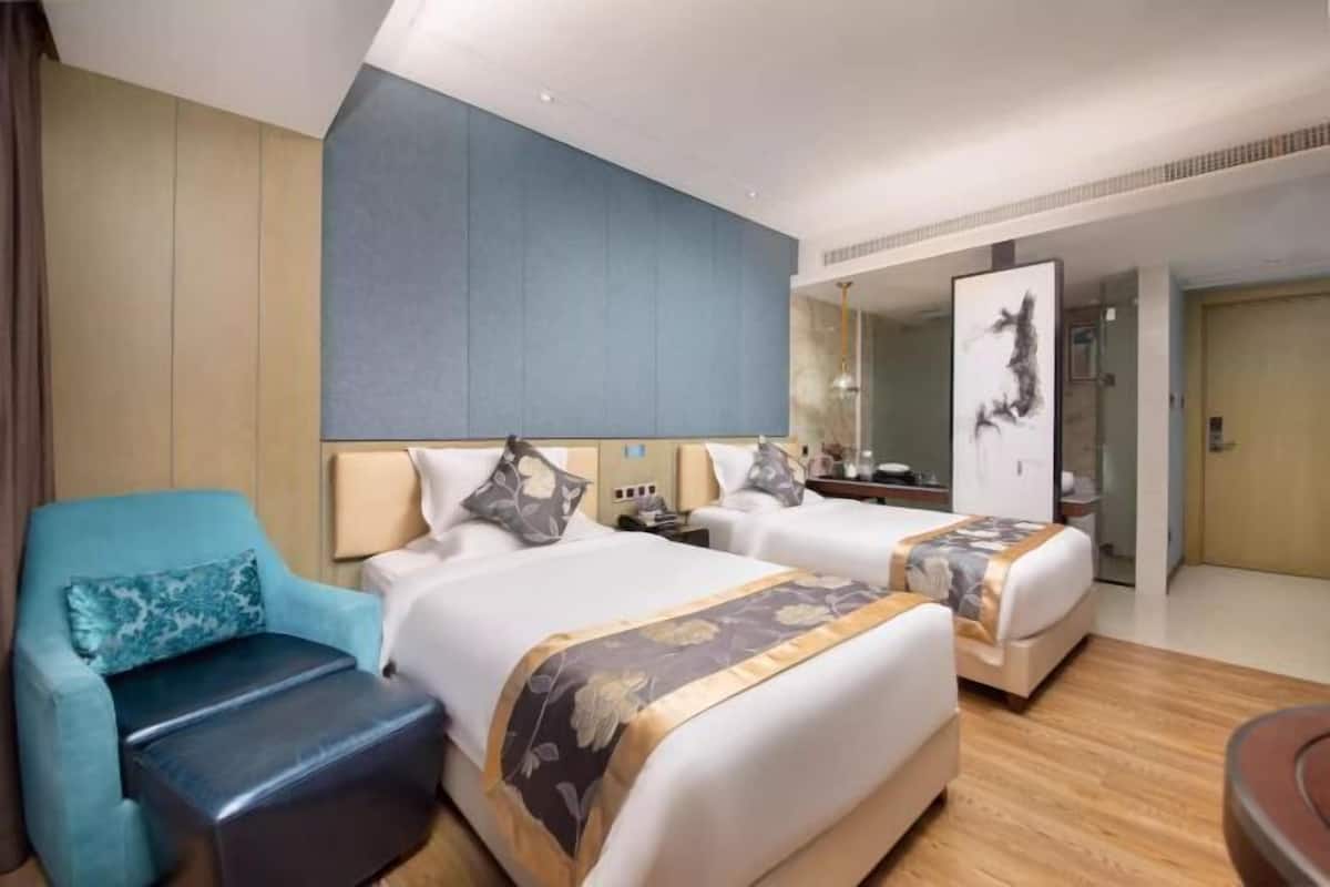 A hotel room with two beds, a sofa, a desk, and a large mirror.