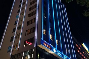 Un edificio de varios pisos con letreros iluminados y ventanas.