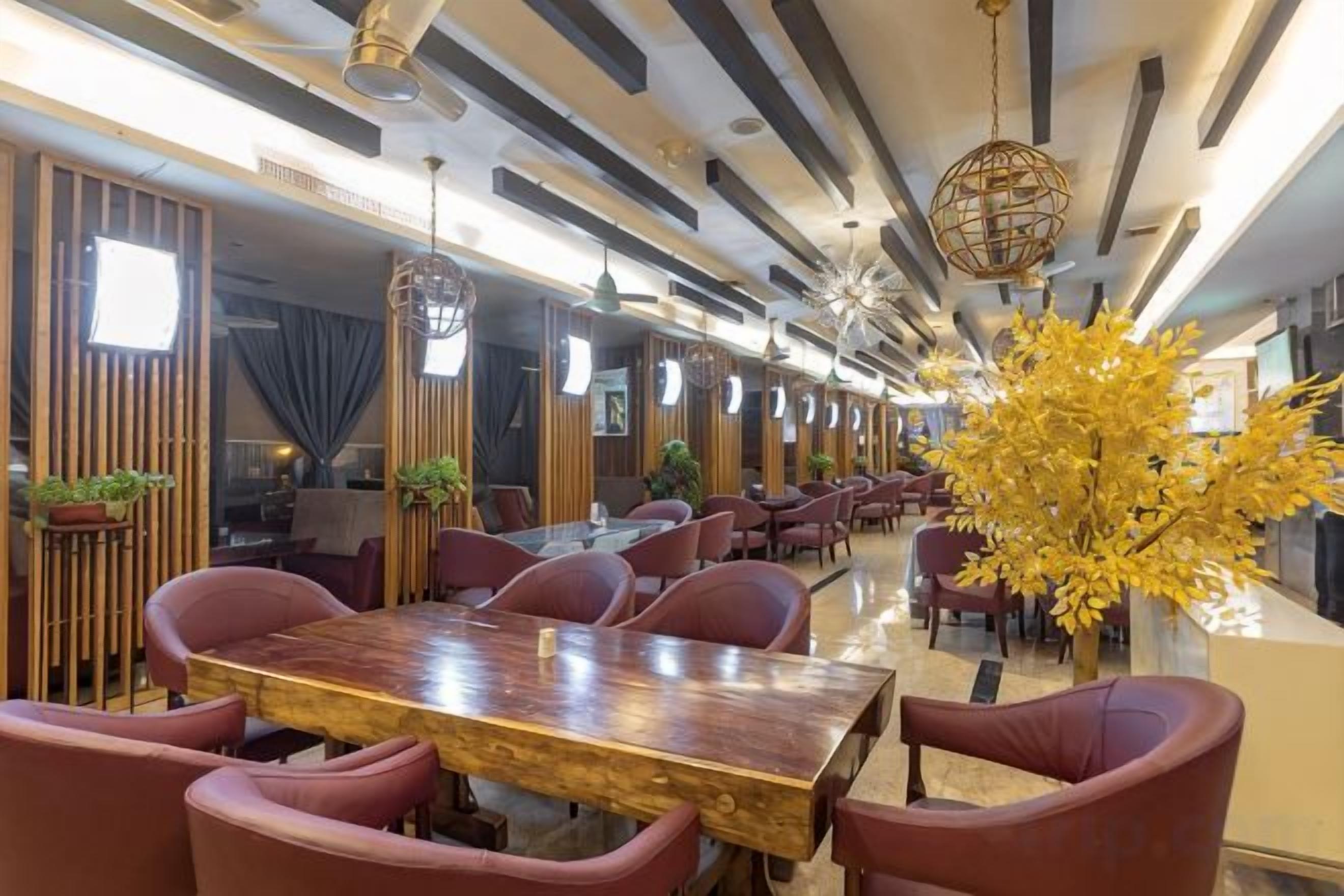 Un restaurante con una larga mesa de comedor, sillas rojas y una planta decorativa.