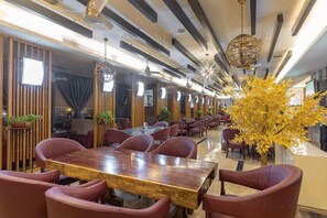 Un restaurante con una larga mesa de comedor, sillas rojas y una planta decorativa.