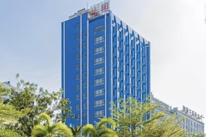 Un edificio alto de color azul con muchas ventanas y un letrero rojo en la parte superior.