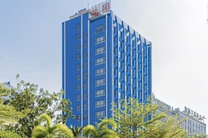 Un edificio alto de color azul con muchas ventanas y un letrero rojo en la parte superior.