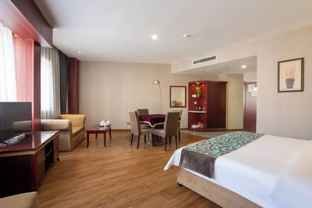 A hotel room with a bed, a desk, a chair, a dining table, and a wardrobe.