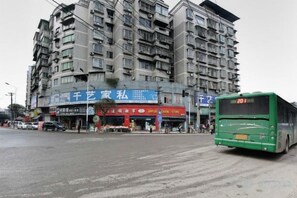 A multi-story building with commercial signage, a green bus in front, and a clear road. - Chongqing Ronghua Hotel (Jiangjin Passenger Transport Center Branch) (Chongqing)