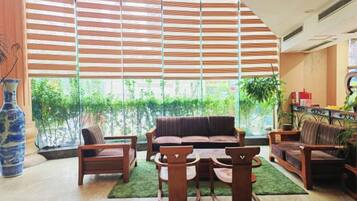 A spacious living area with a large window, a sofa, a coffee table, and a bookshelf.