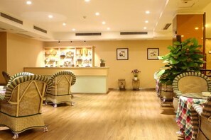 A hotel lobby with wicker chairs, a reception desk, and a large potted plant. - Chongqing Ronghua Hotel (Jiangjin Passenger Transport Center Branch) (Chongqing)