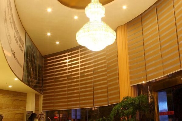A hotel lobby with a large chandelier, striped wall panels, and a large poster. - Chongqing Ronghua Hotel (Jiangjin Passenger Transport Center Branch) (Chongqing)