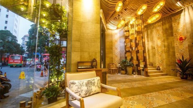 Un hall d’entrée avec un fauteuil en bois, un piano et un tapis à motifs.