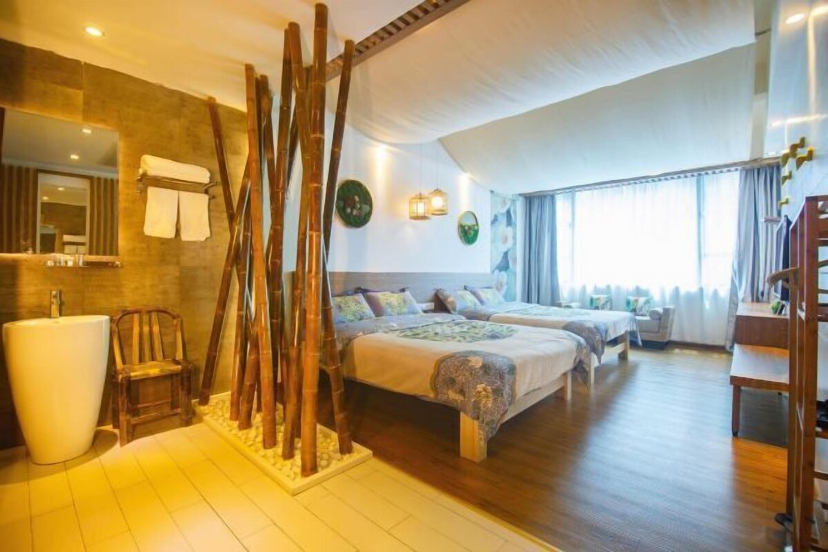 Ein Hotelzimmer mit einem großen Bett, einer Sitzecke, einem Badezimmer mit großem Waschbecken und Blick ins Freie.