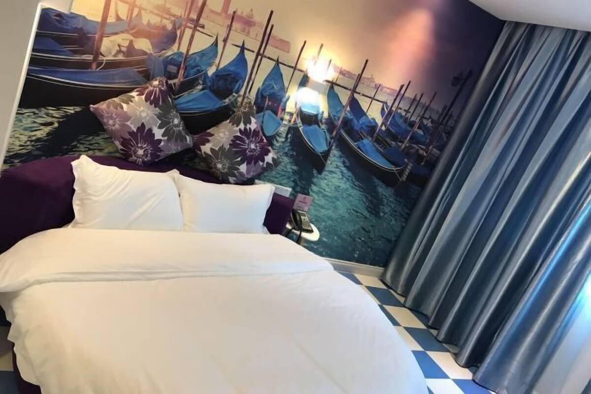 Una habitación de hotel con una cama, un mural de barcos y un suelo a cuadros.