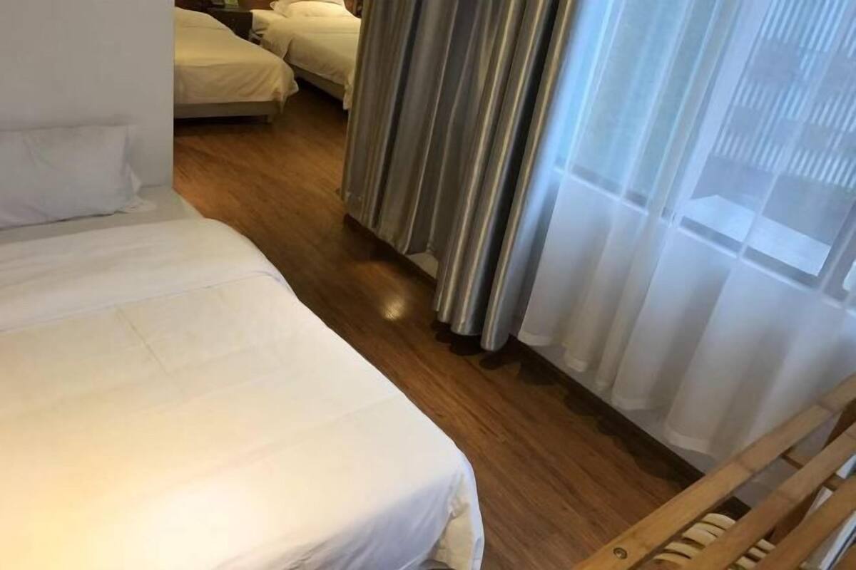 Una habitación de hotel con una cama individual, suelo de madera y ventana con cortinas.