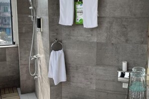 Ein modernes Badezimmer mit Dusche, Handtuchhalter und Pflegeprodukten.