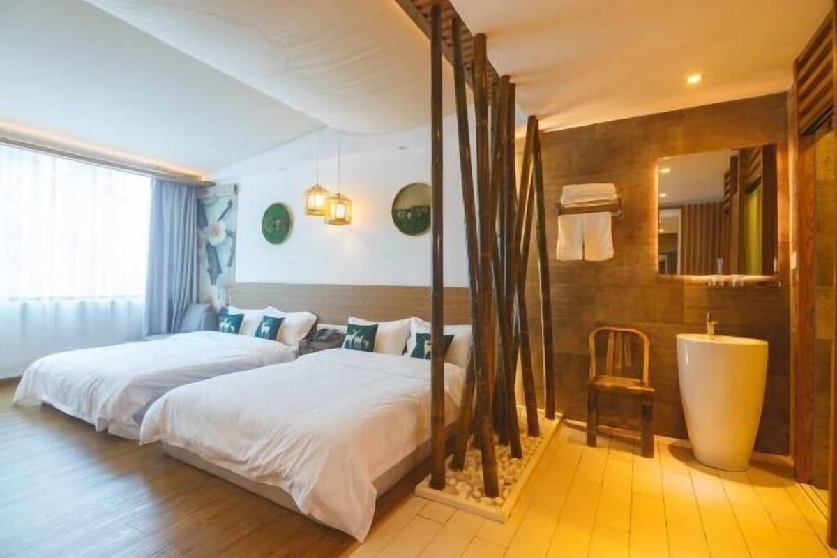 Una habitación de hotel con dos camas, un espejo grande, un lavamanos y una silla.