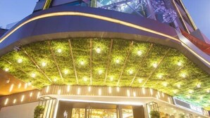 Un bâtiment moderne doté d’une entrée incurvée, d’un plafond recouvert d’un gazon artificiel vert et d’une signalétique bien visible.