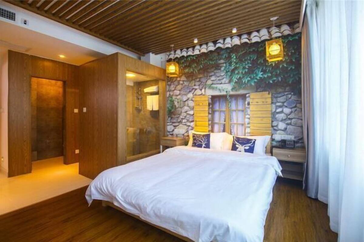 Un dormitorio con una cama, paredes de madera, una pared de piedra con ventana y una chimenea de piedra.
