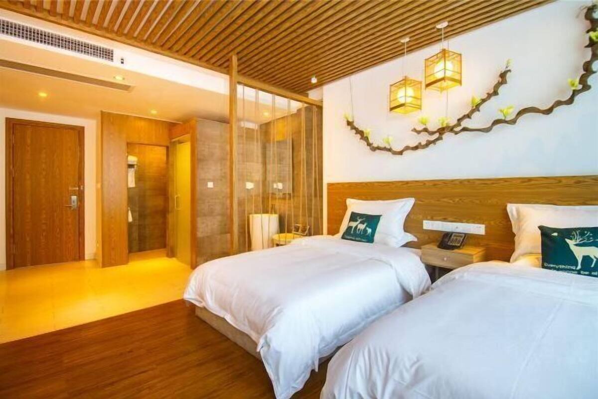 Habitación de hotel con dos camas, techo de madera y una pared decorativa con luces.