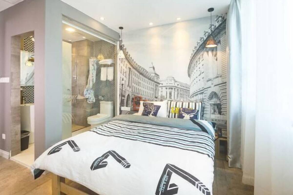 Un dormitorio con cama, cabina de ducha de vidrio y un mural con vista a la ciudad.