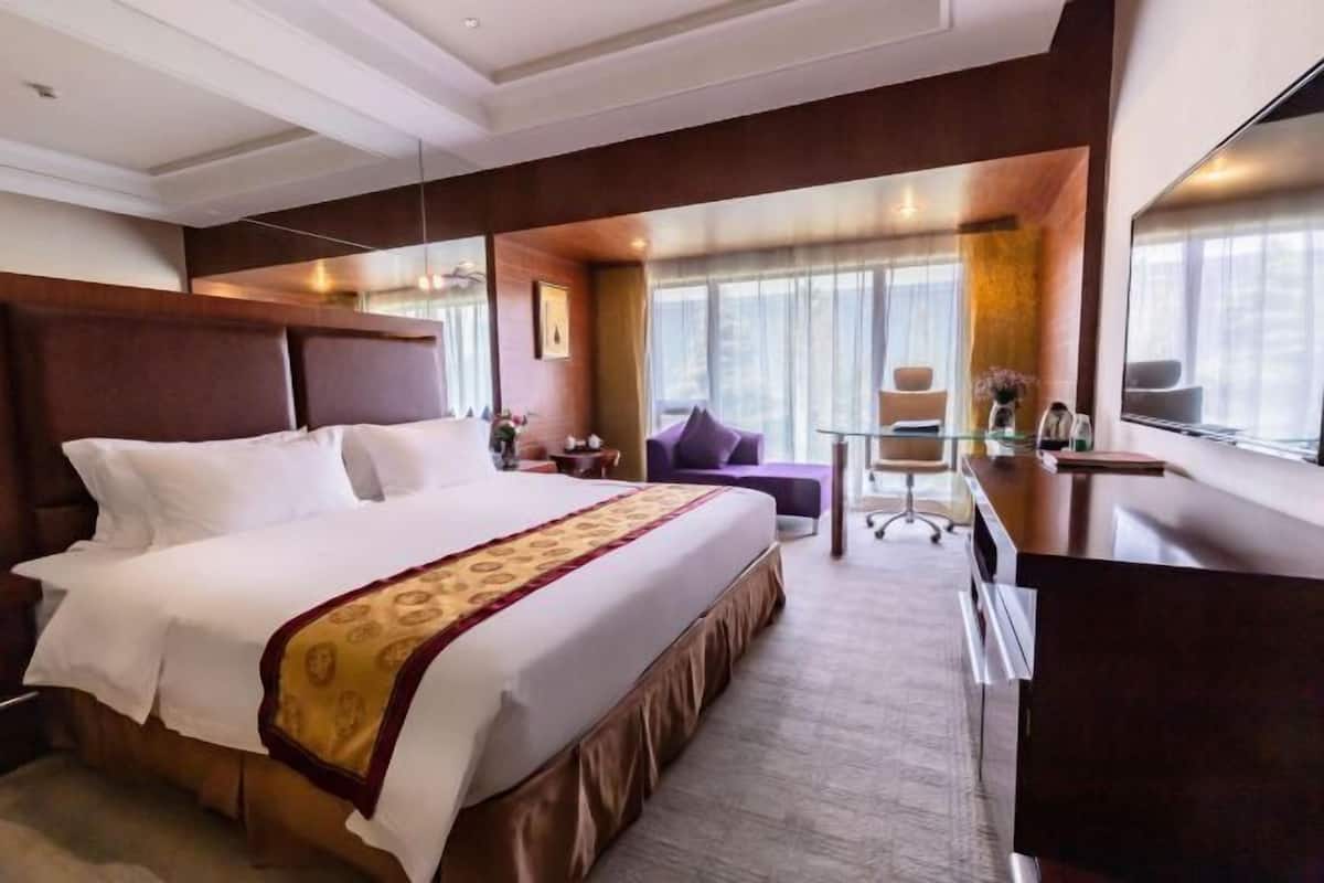 Une chambre d’hôtel avec un grand lit, un bureau, une chaise et une grande fenêtre.