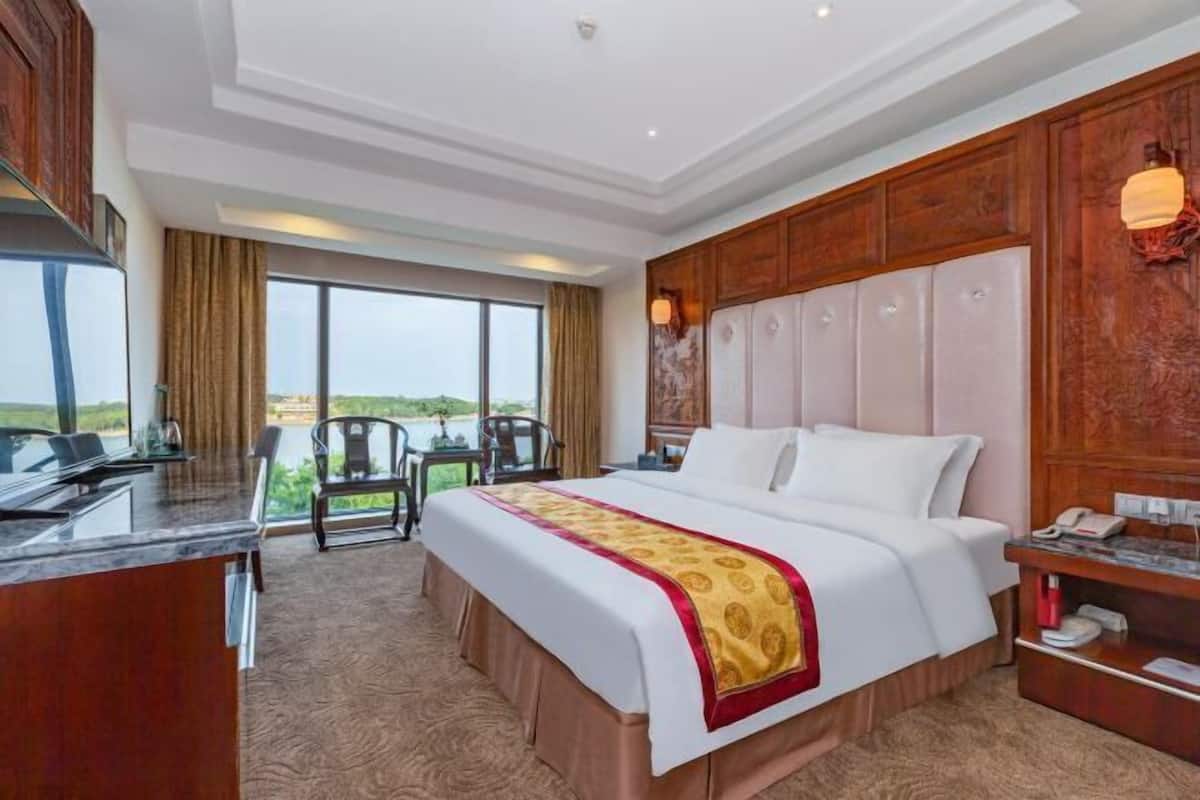 Une chambre d’hôtel avec un grand lit, un bureau, une chaise et une vue sur l’extérieur.