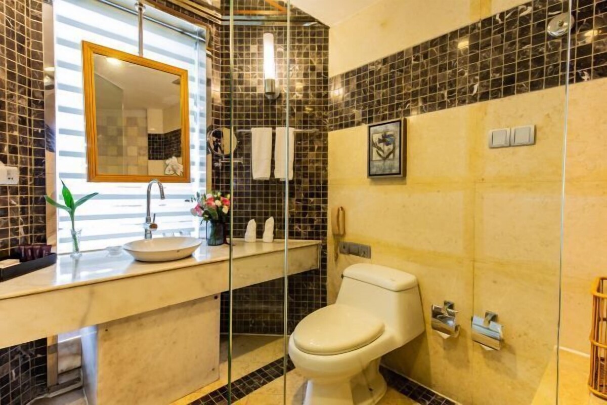 A bathroom with a glass shower enclosure, a white toilet, a sink with a mirror, and a tiled backsplash.