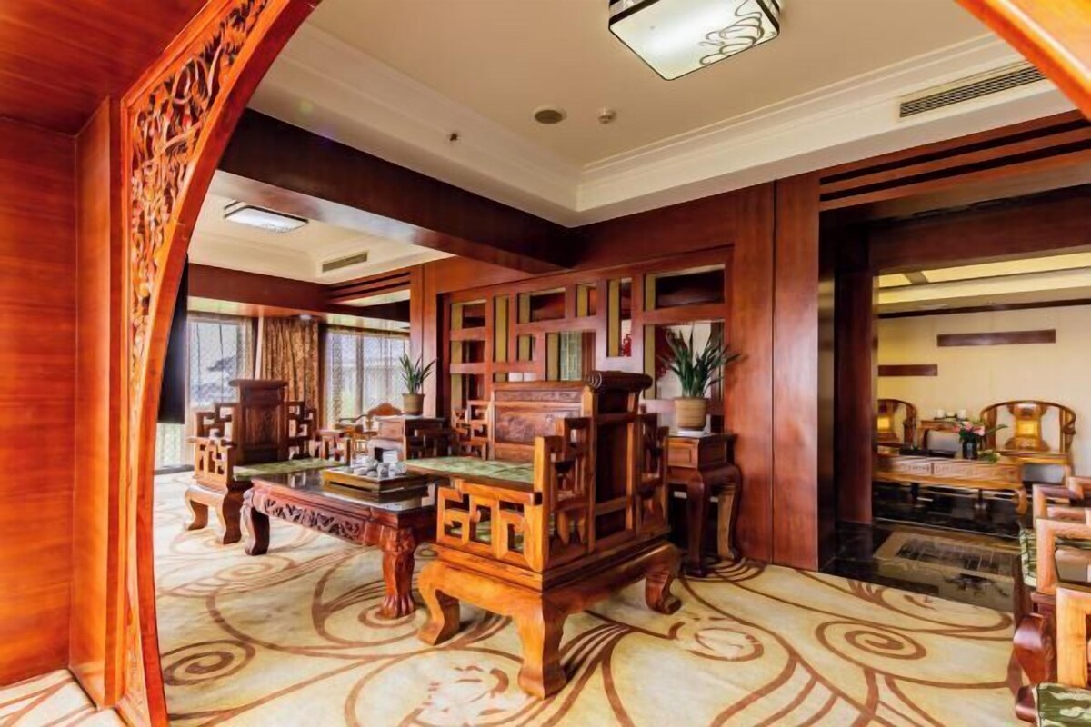 A traditional wooden interior with a large wooden cabinet, a sofa, and a patterned carpet.
