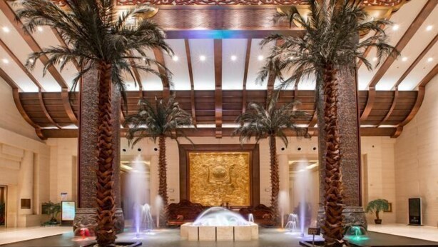 A lobby with a central fountain, palm trees, and a large decorative wall. - Apollo Regalia Hotel & Resort (Yueyang)