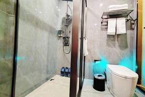 A modern bathroom with a glass shower enclosure, a toilet, and a towel rack with towels. - Sanming Holiland Landscape Hotel (Sanyuan District Qilin Mountain) (Sanming)