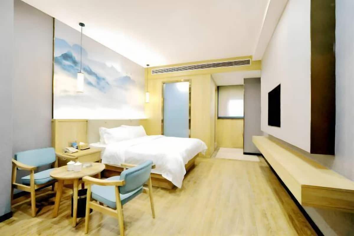 A hotel room with a bed, a desk, a chair, a TV, and a large window.