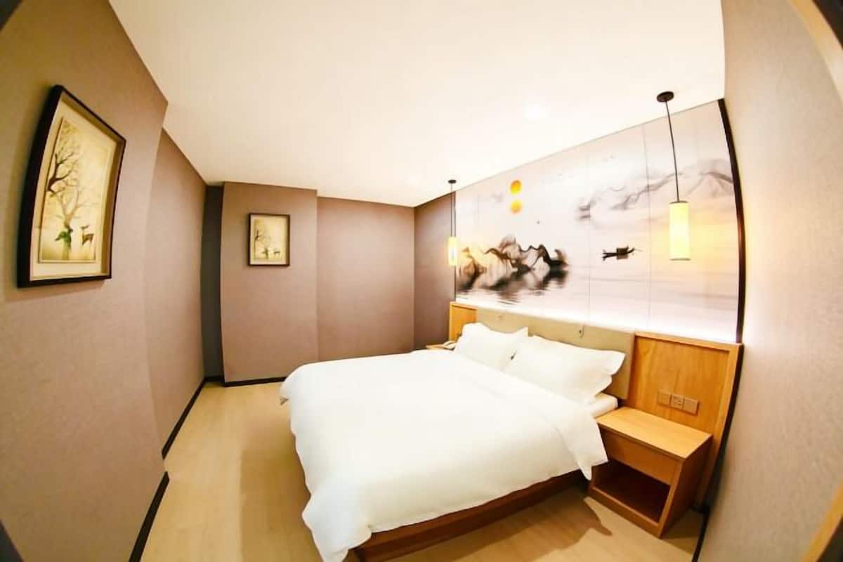 A bedroom with a bed, a nightstand, a wall-mounted shelf, and a framed picture.