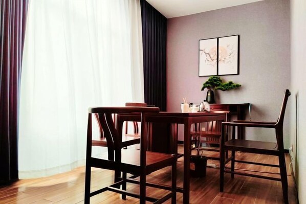 A dining area with a wooden table and chairs, a potted plant, and a wall-mounted artwork. - Sanming Holiland Landscape Hotel (Sanyuan District Qilin Mountain) (Sanming)