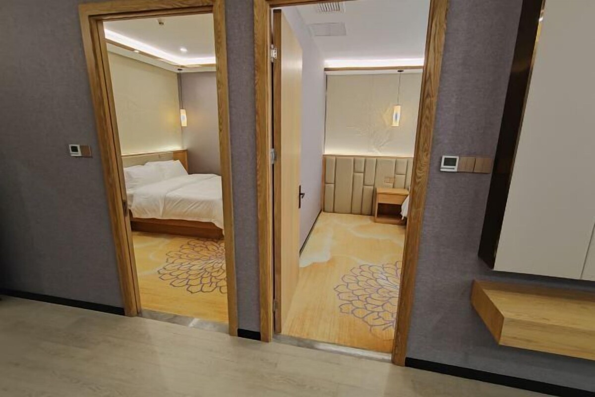 A hotel room with a bed, a small seating area, and a vanity with a mirror.