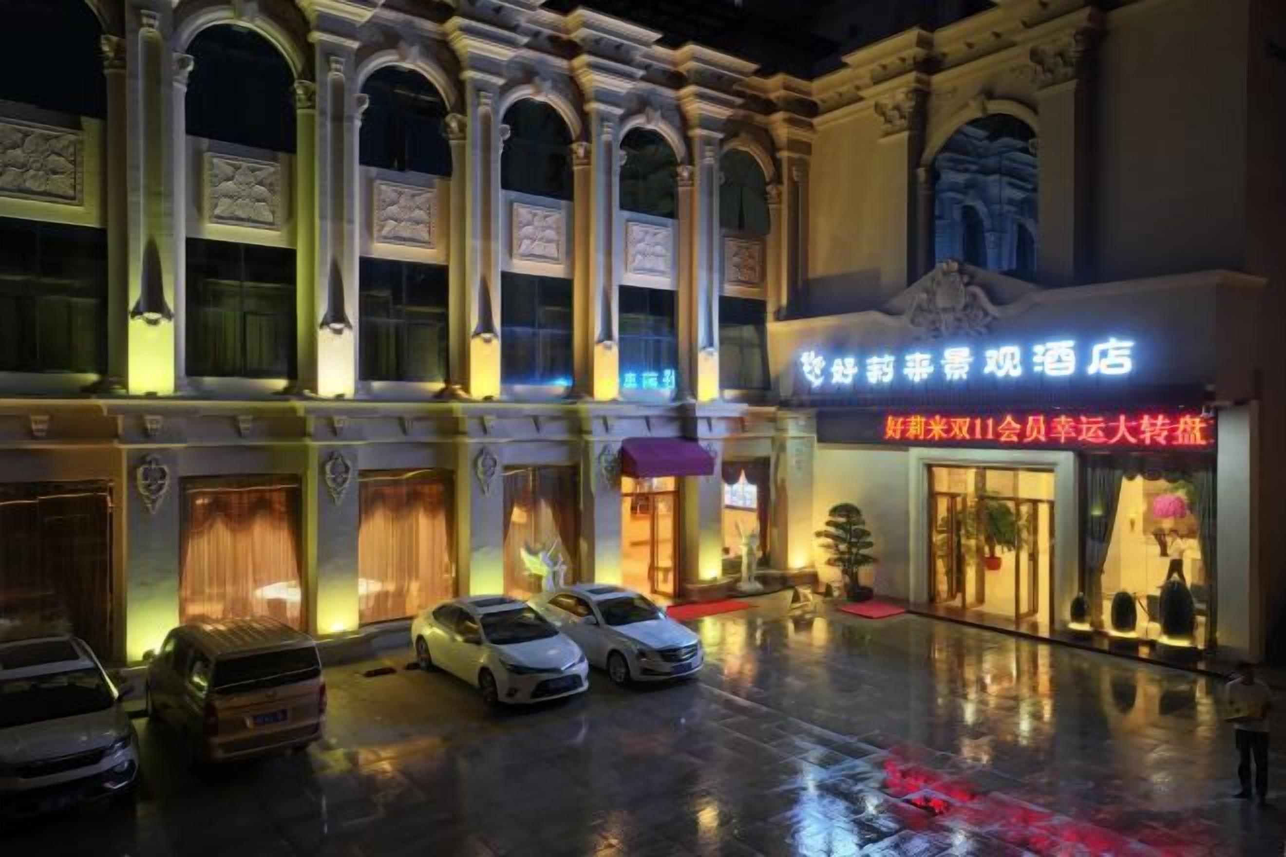 A hotel facade with arched windows and a neon sign.