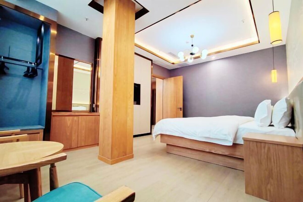 A modern hotel room with a bed, a desk, and a seating area.